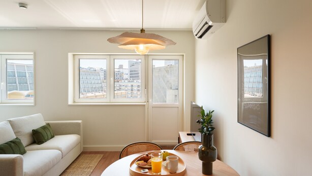 Un salon moderne comprenant un canapé, une table à manger et une grande fenêtre donnant sur la ville.