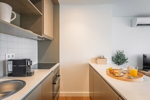 A modern kitchen with a coffee machine, toaster, and a breakfast tray with croissants, fruit, and orange juice. - Bom Sucesso Executive Flat 5 1 by Feel Porto (Porto)