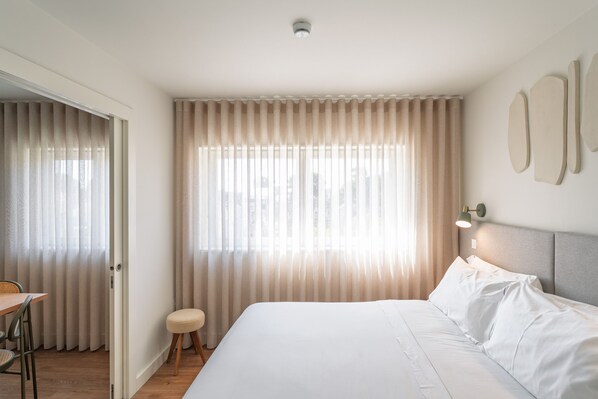 A hotel room with a large bed, a desk, a chair, and a small stool. - Bom Sucesso Executive Flat 5 1 by Feel Porto (Porto)