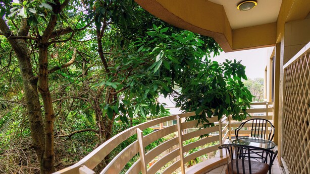 A balcony with a curved railing, a glass table, and two chairs.