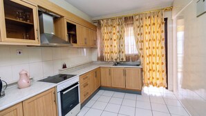 A kitchen with wooden cabinets, a stove, a sink, and a kettle.