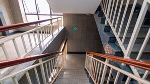 A staircase with a handrail, a sign indicating a wheelchair-accessible route, and a view of the building's interior.