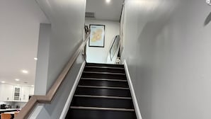 Een trap met houten treden en een leuning, die uitkomt op een plateau met een ingelijste kaart.