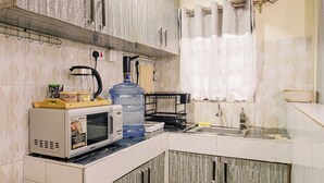 Une cuisine moderne avec des meubles blancs, un grand distributeur d’eau, un four à micro-ondes et une cuisinière à gaz.