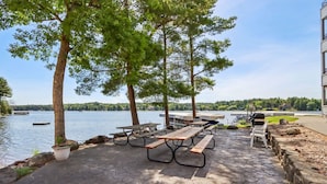 Une terrasse au bord du lac, dotée de tables de pique-nique et d’un barbecue, avec vue sur un lac paisible.