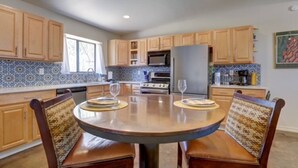 Una cocina con armarios de madera, una isla central y un comedor con sillas estampadas.