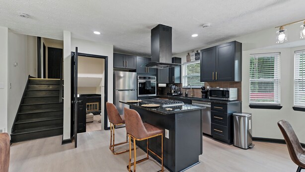 A modern kitchen with a central island, stainless steel appliances, and dark cabinetry. - Atlanta Vacation and Family Stay, Sleeps 10, King Beds, near the Atlanta Airport (Atlanta)
