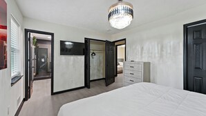 A bedroom with a bed, a dresser, a television, and a chandelier. - Atlanta Vacation and Family Stay, Sleeps 10, King Beds, near the Atlanta Airport (Atlanta)