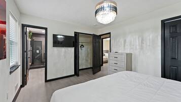 Une chambre à coucher avec un lit, une commode, un téléviseur et un lustre.