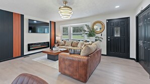 A modern living room with a sectional sofa, a fireplace, and a large window. - Atlanta Vacation and Family Stay, Sleeps 10, King Beds, near the Atlanta Airport (Atlanta)
