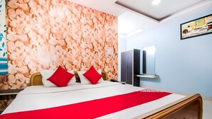 Ein Hotelzimmer mit einem Bett, einem hölzernen Kopfteil, einer Wand mit strukturierter Blumenwallpaper und einem Spiegel über dem Bett.