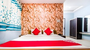 Ein Hotelzimmer mit einem großen Bett, einer Wand mit floralem Muster, einem Kleiderschrank und einem Fernseher.