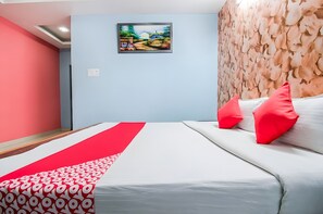 A hotel room with a bed, red and white patterned bedspread, and a painting on the wall. - HOTEL PRADHAN INN (Siwan)