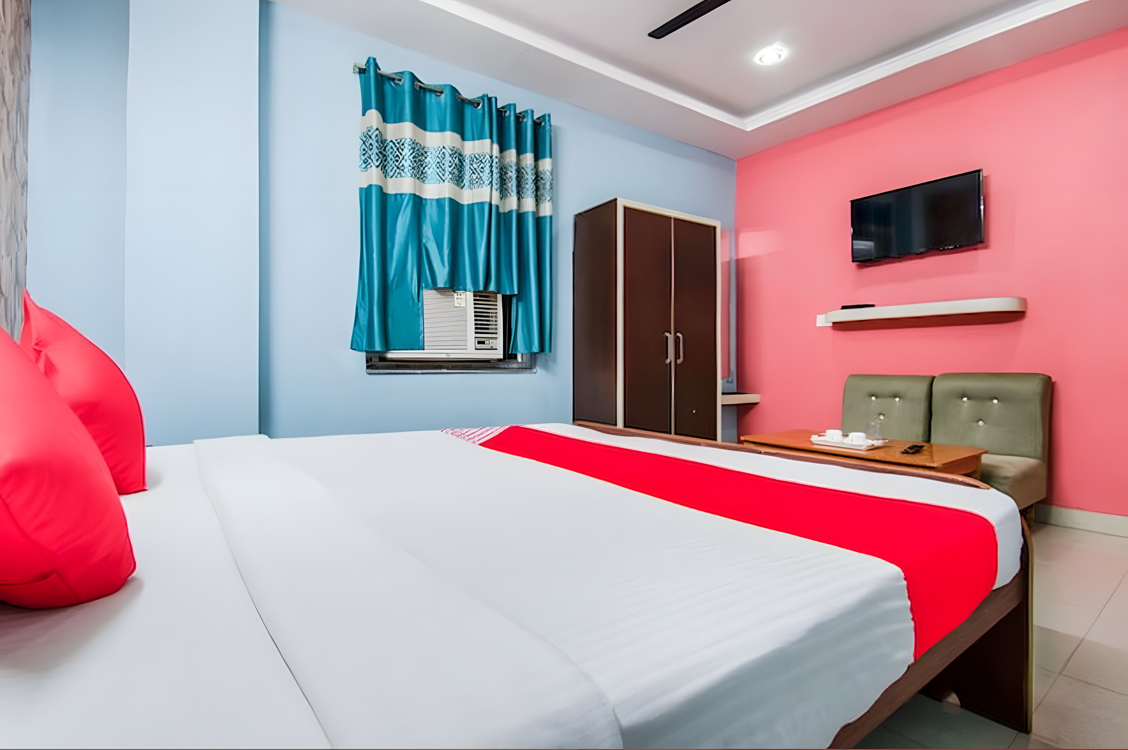A hotel room with a bed, a wardrobe, a television, and a seating area.