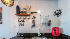 A kitchen with a black granite countertop, a sink, a coffee maker, a red toaster, and a dish rack with utensils.
