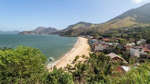 A coastal town with a beach, houses, and hills in the background.