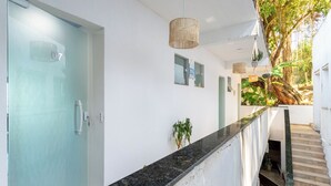 A modern hallway with a glass door, a black marble counter, and a staircase leading to a covered outdoor area with plants.