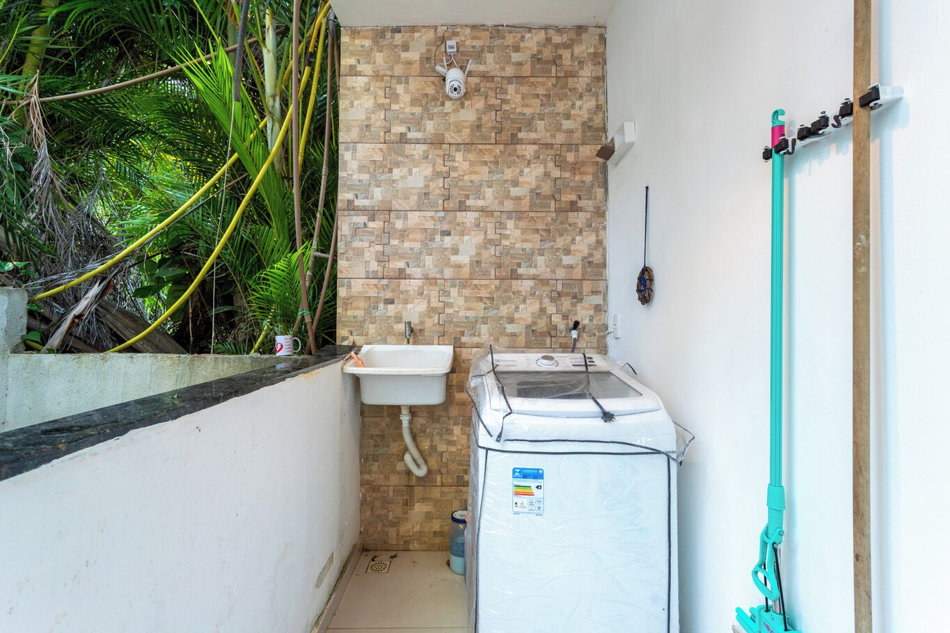 A compact bathroom with a sink, a washing machine, and a shower area.
