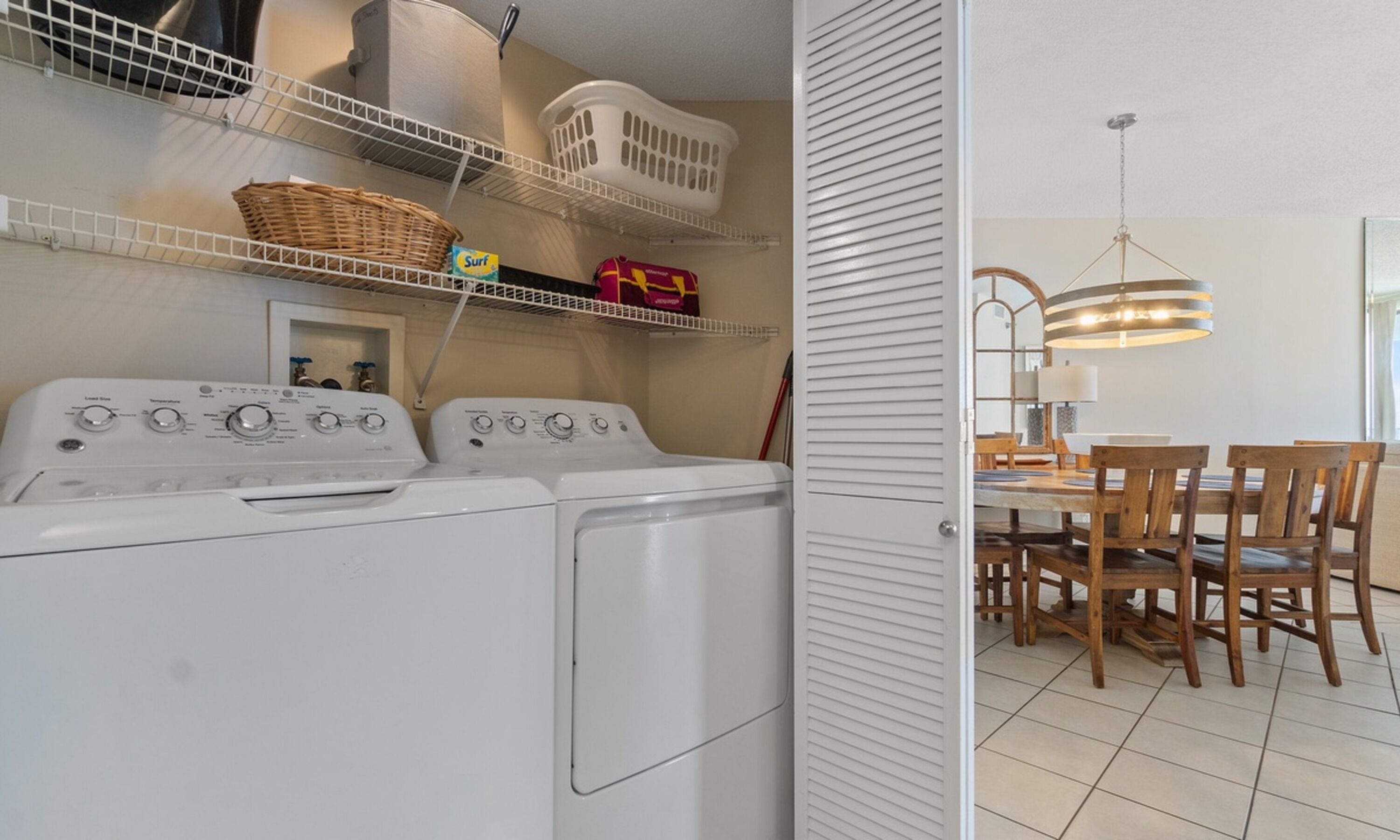 A laundry area with two front-loading washing machines, a drying rack, and a basket.