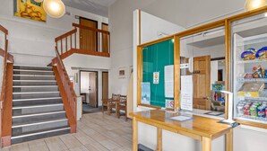 Un espace d’accueil avec un bureau en bois, un tableau d’affichage vert et un distributeur automatique.