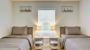 Ein Schlafzimmer mit zwei Betten, einem Fenster mit Jalousien und zwei Wandlampen.