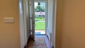 A hallway leading to a door with a view of a house and lawn.