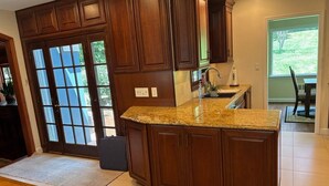 A kitchen with wooden cabinets, a granite countertop, and a large window.