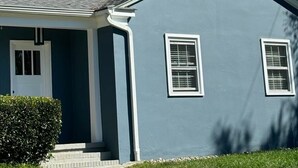 A single-story house with a dark blue exterior, white trim, and a small front porch.