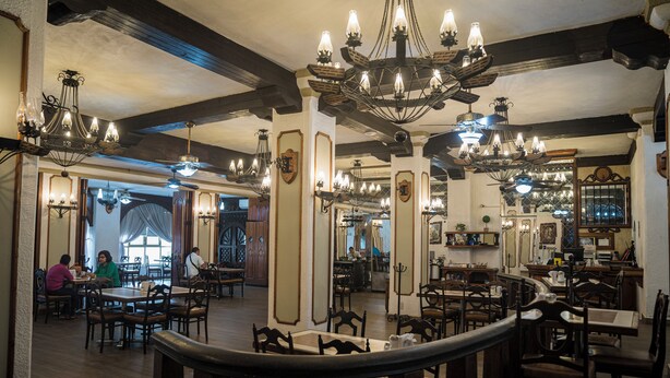 A restaurant with wooden tables and chairs, chandeliers, and a staircase. - HOTEL SIERRA GORDA (Ciudad Victoria)