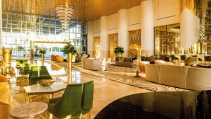 A spacious lobby with a large chandelier, modern furniture, and large windows offering a view of the city. - Elegant Oceanfront 3BR Suite in Cancun – Luxury & Space for 8 Guests (Cancún)
