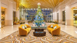 A lobby with a large Christmas tree, two sofas, and a patterned rug. - Elegant Oceanfront 3BR Suite in Cancun – Luxury & Space for 8 Guests (Cancún)