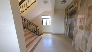 A staircase with a handrail, a window with natural light, and a wall with a marble-like pattern. - Kiandani Hotel Machakos (Machakos)