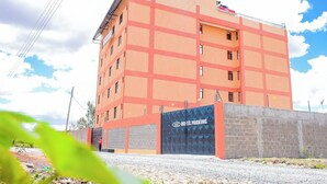 A multi-story hotel with a distinctive orange and red facade, featuring a prominent entrance gate labeled "HOTEL PARKING". - Kiandani Hotel Machakos (Machakos)