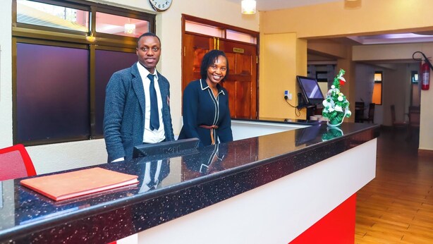 A reception desk with a clock, a private door, and a small plant. - Kiandani Hotel Machakos (Machakos)