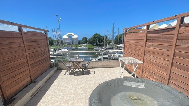 Une terrasse sur le toit avec un jacuzzi gonflable rond, une petite table et des chaises.