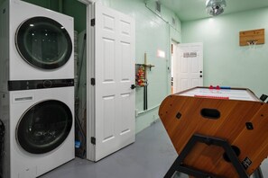 A laundry room with two washing machines, a door labeled 'GAME ROOM,' and a foosball table. - Heated Pool/5 mins to St Pete Beach-Slps 10 (St. Petersburg)