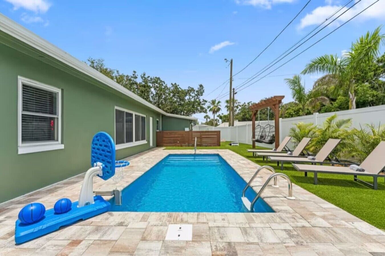 Une piscine avec un toboggan, des chaises longues et une pergola.