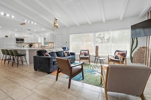 A modern living room with a sofa, chairs, a coffee table, and a kitchen area with a bar.