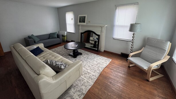Una sala de estar con un sofá color beige, un sofá gris, una mesa de centro, una chimenea y una silla.