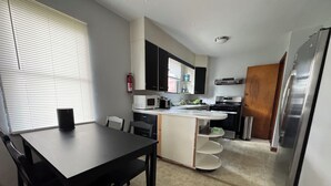 Una cocina compacta con comedor, microondas, estufa y refrigerador.
