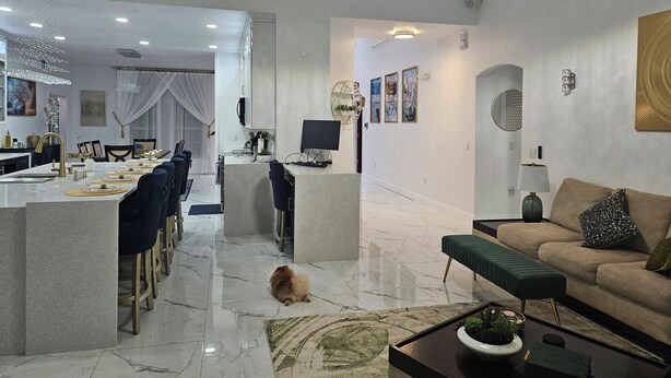 A spacious living area with a high ceiling, a balcony, and a dining area with a long table and chairs. - Beautiful 6 Room House - 10 Minutes from Disney World Parks (Kissimmee)