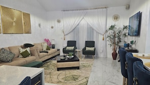Una sala moderna con un sofá, dos sillones, una mesa de centro y un comedor con sillas y una mesa.