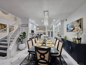 Un comedor con una mesa larga, sillas y una escalera.