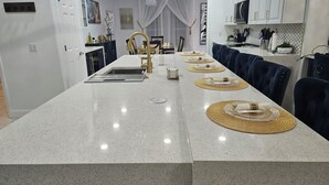 A modern kitchen with a central island, white cabinetry, and a dining area with blue upholstered chairs. - Beautiful 6 Room House - 10 Minutes from Disney World Parks (Kissimmee)