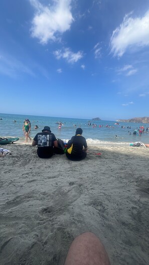 A beach with people swimming and walking on the sand.
