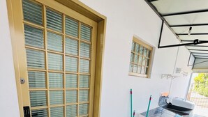 Una entrada limpia y bien conservada, con puerta de cristal, un ventanal pequeño y suelo de baldosas.