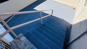 Una escalera con escalones azules y una barandilla de metal que conduce a una puerta blanca.