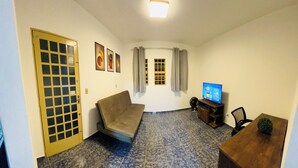 Una habitación con sofá, televisor, una mesita y una puerta con ventana.