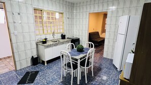 Una cocina compacta con armarios blancos, un lavamanos y una zona de comedor con mesa y sillas.