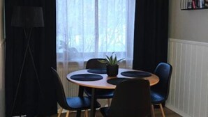 A dining area with a round table, four chairs, a potted plant, and a ceiling light fixture. - Independent apartment with kitchen (Norrbottens län)
